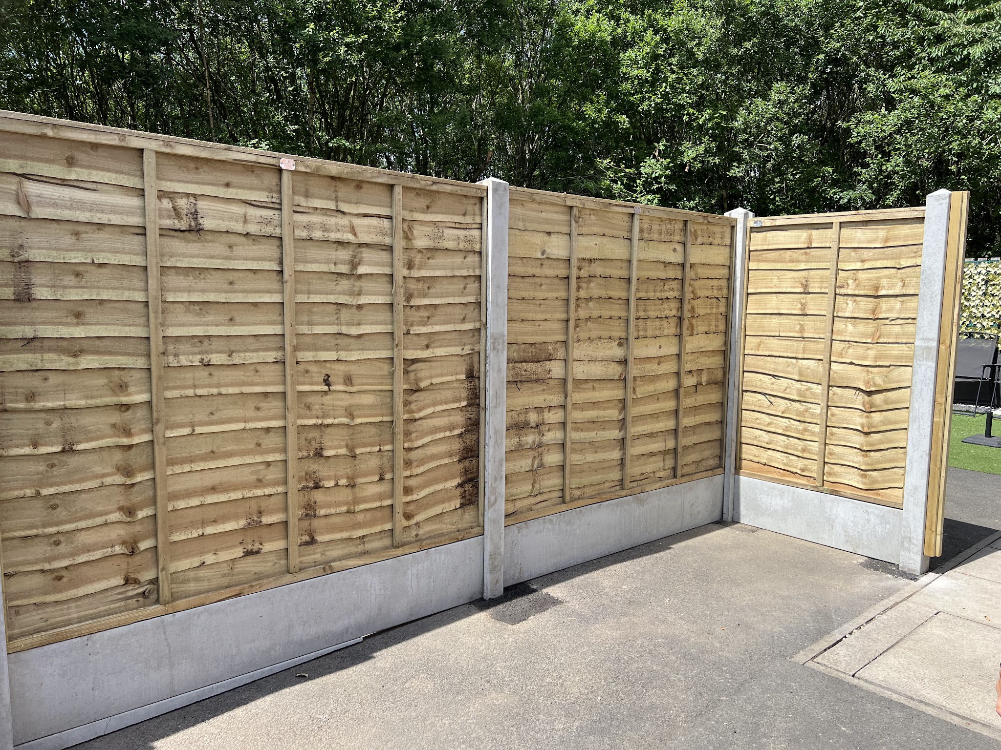 A timber panel fence with concrete posts and a neatly fitted corner